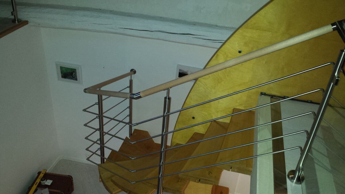 Escalier colimaçon équipé d'une rambarde inox avec main courante en hêtre, poteau fixés à travers les marches