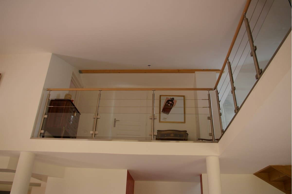Garde-corps sur mezzanine avec verre et câbles inox, main courante en chêne